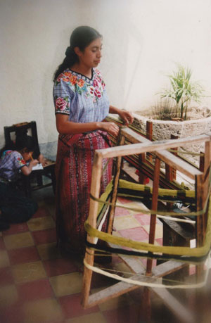 Guatemalan Weaver Utilizing a Yarn Winder to Wrap Yarn Around Pegs on Warping Board